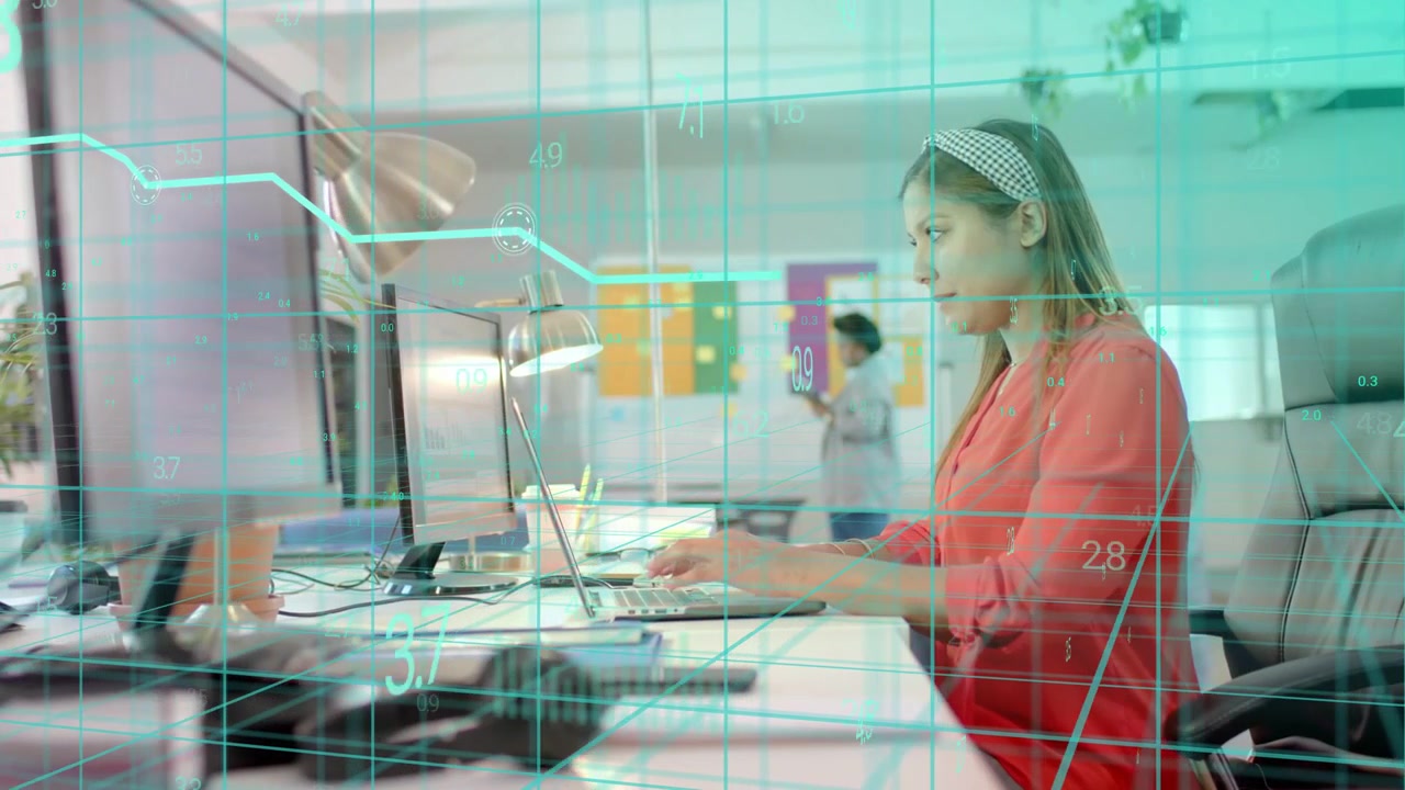 Seated worker typing shifting inputs, updating teal grid and line graph monitoring business metrics