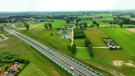 Aerial-view-of-a-highway-cutting-through-rural-countryside-with-adjacent-residential-areas