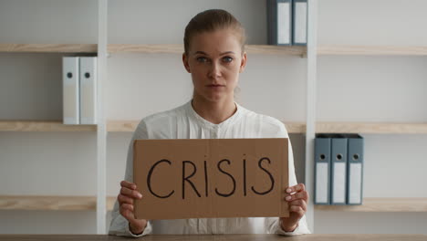 woman holding sign saying 'crisis' in office