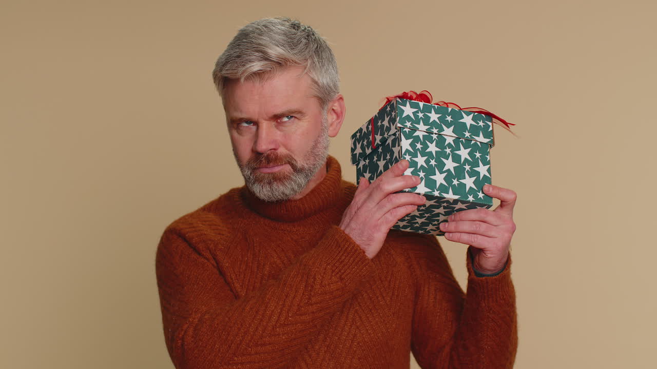 행복한 남자는 선물 상자를 열고, 생일 놀라움을 풀고, 큰 행복과 놀라움을 표현합니다.