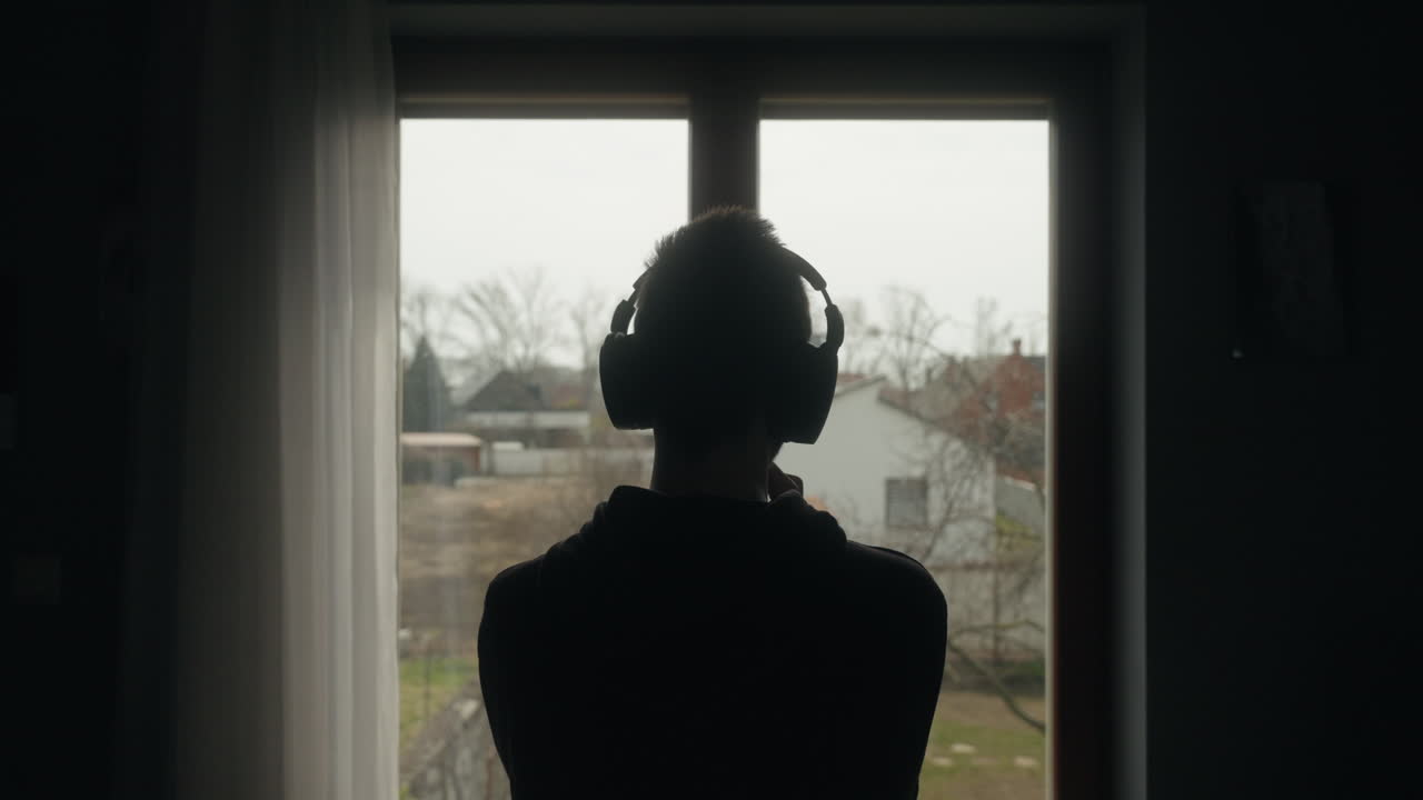 Student listening music while looking out of a window