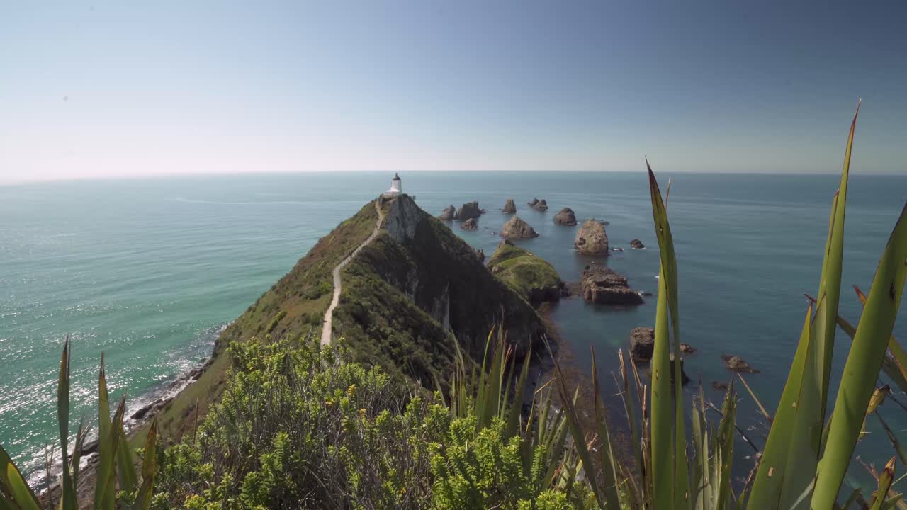 vista panorámica del faro y las islas rocosas en el océano durante el verano en nueva zelanda
