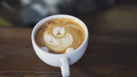 hands of a bartender drawing with stick in a white cup of cappuccino. process of making nice morning cappuccino coffee