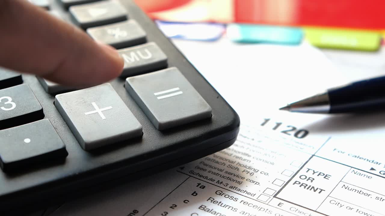 1120 세금 양식은 계산기와 펜으로 작성됩니다.