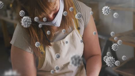 animación de células de covid-19 sobre una mujer que trabaja en un estudio de cerámica con una máscara facial