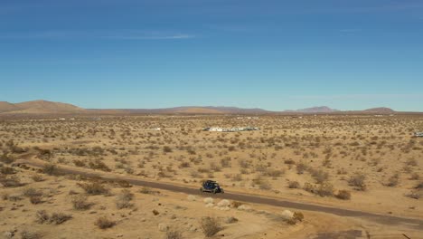 an off-highway vehicle driving along dirt trails in the mojave desert landscape - aerial view