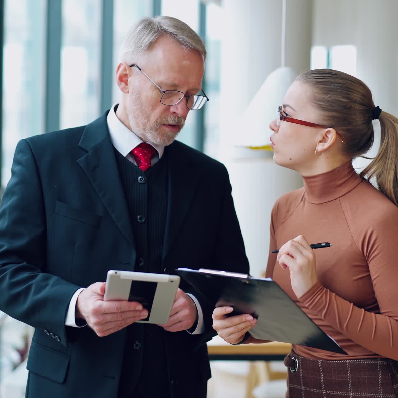 Mature businessman and female secretary. Senior entrepreneur in elegant costume talking to a beautiful woman in modern office.