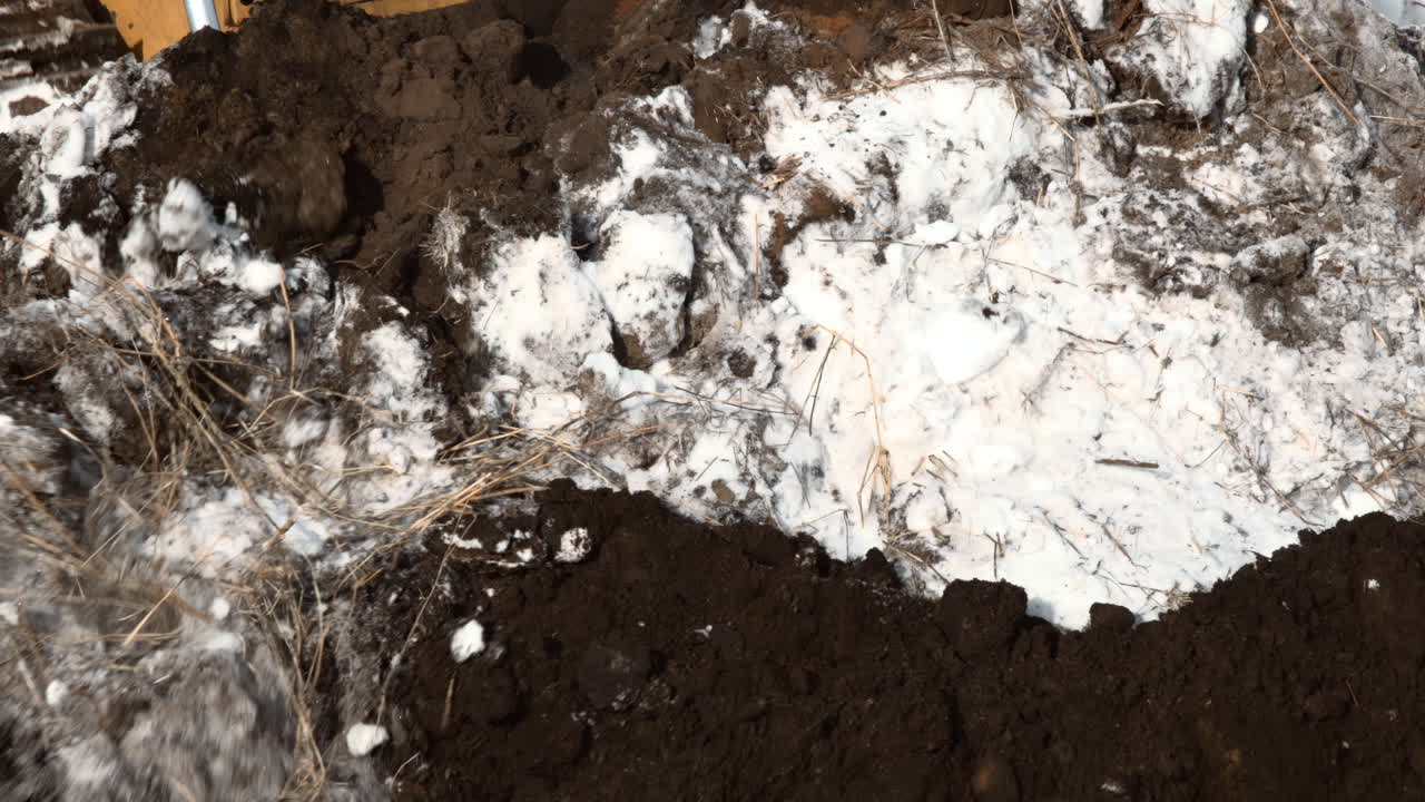 Planierraupe schiebt Erde und Schnee auf Baustelle