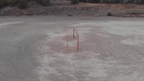 Aéreo:-Volando-Alrededor-De-La-Portería-De-Fútbol-Vacía-Durante-La-Puesta-De-Sol-En-Un-Campo-Duro