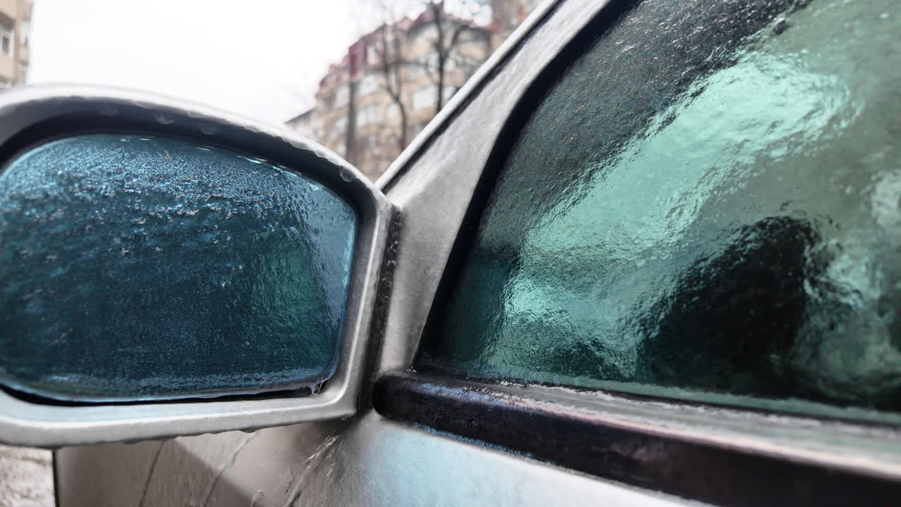 Nahaufnahme eines vereisten Auto-Außenspiegels, von dem Schmelzwasser tropft