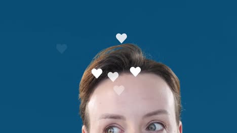 animation von herzformen, die über kaukasischen jungen frauen fliegen, die ihre augenbrauen über blauen hintergrund heben