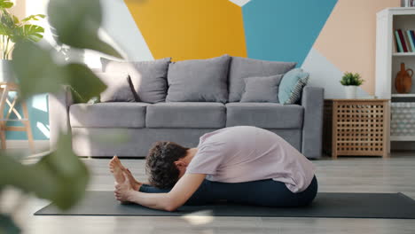 woman doing seated forward bend yoga pose at home