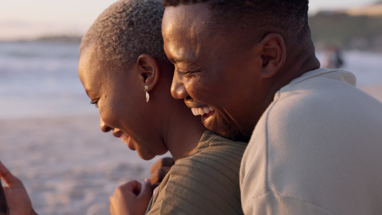una pareja tomando una foto en la playa al atardecer