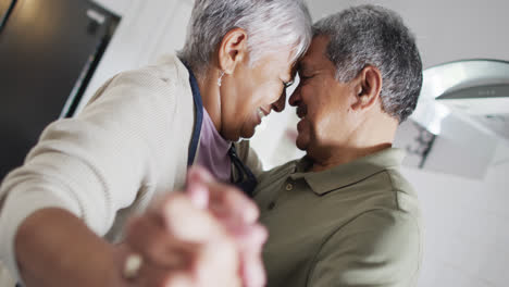 Happy-senior-biracial-couple-dancing-in-kitchen