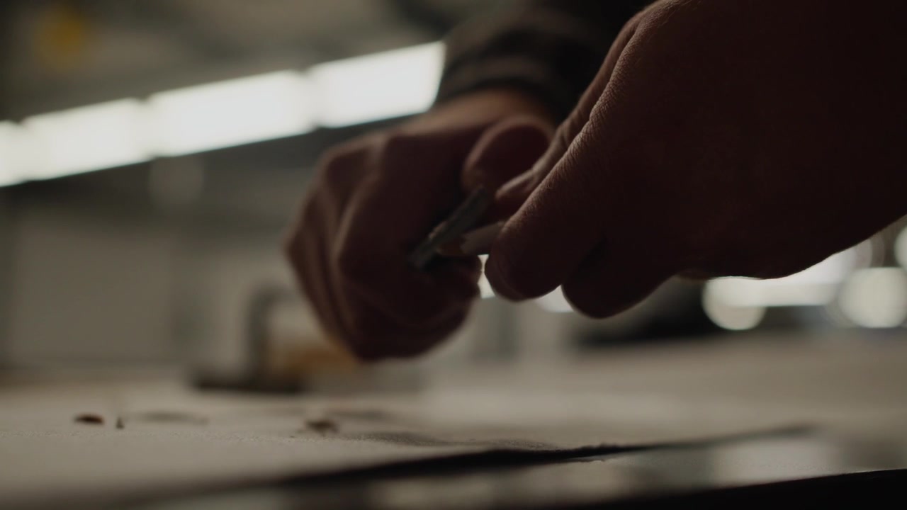 Hand cutting fabric during design process in an industrial factory. Close up of hand cutting fabric as whilst making a pattern