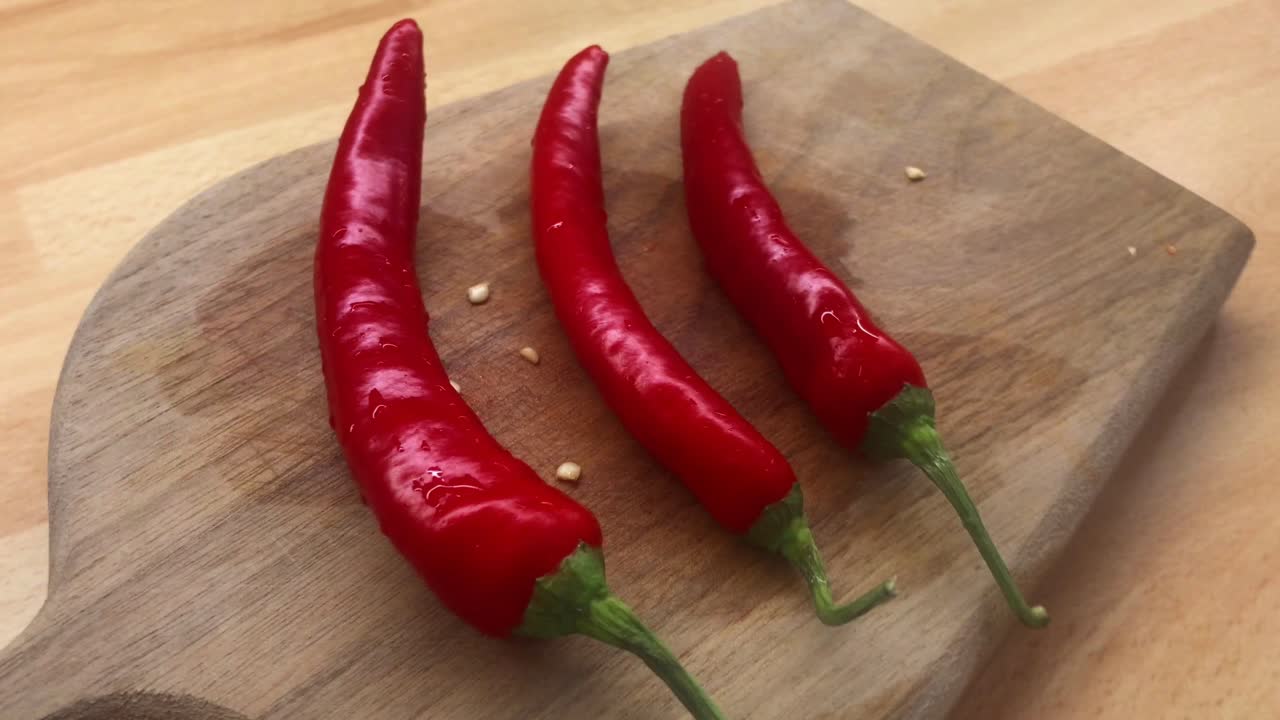 Three Washed Red Chili Peppers Close-up on Wooden Board