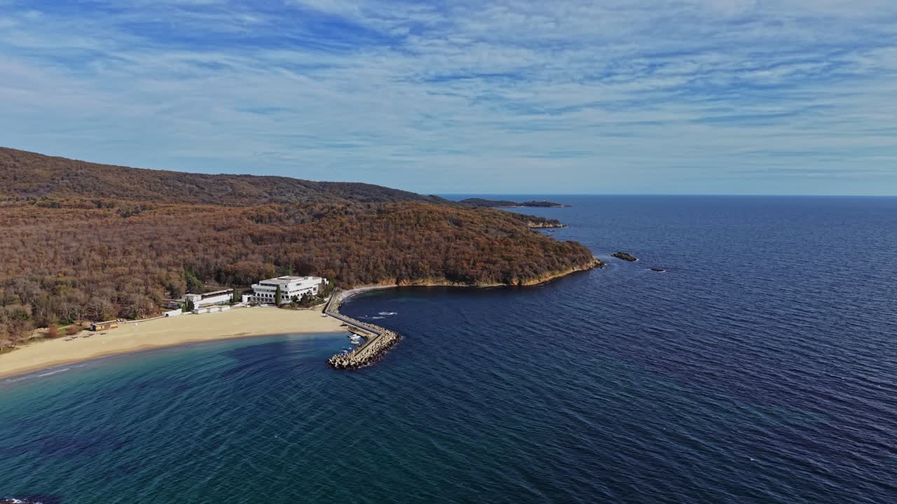 Coastal view of a serene beach and lush forested hills from above