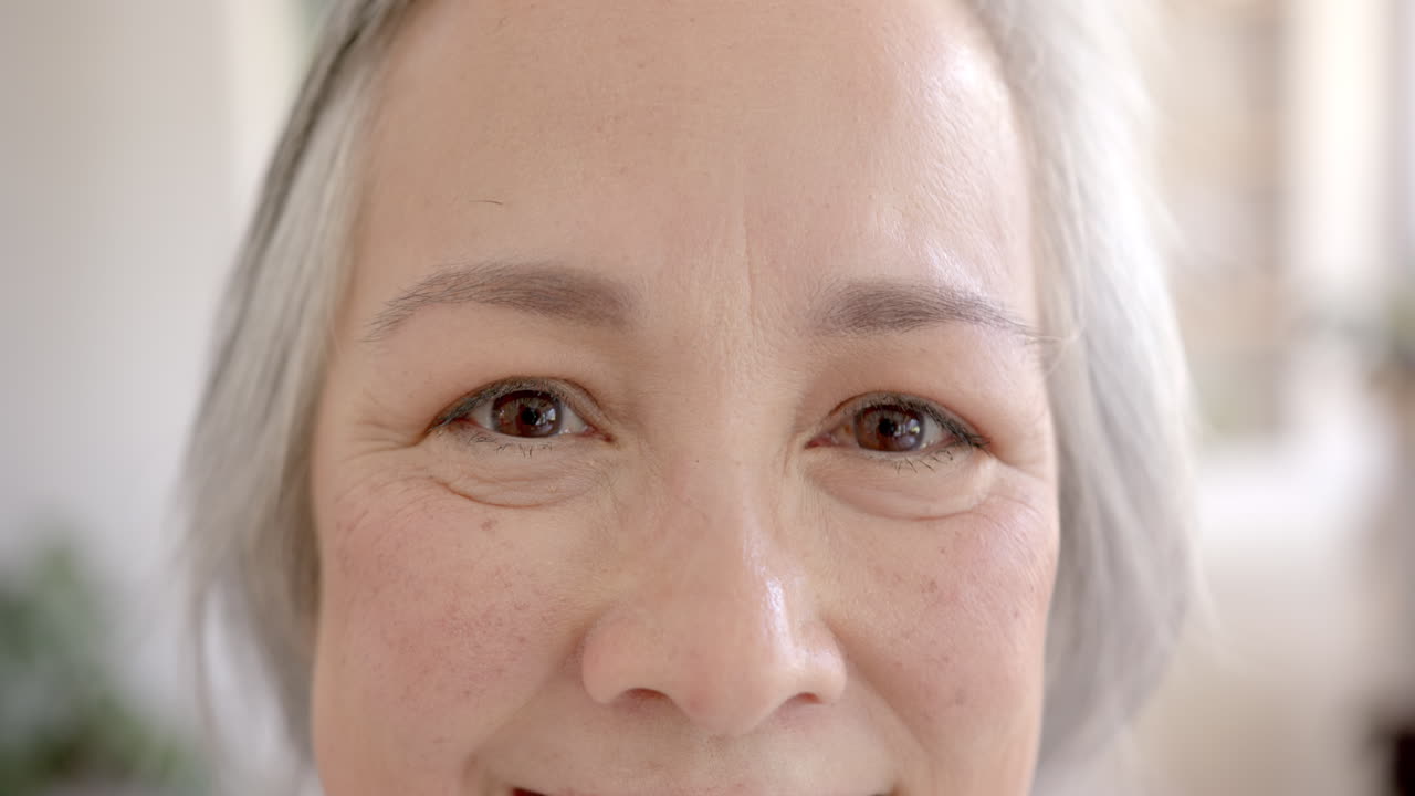 Smiling elderly asian woman with gray hair, close-up of face and eyes
