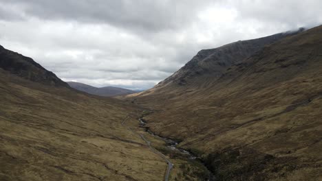 Drone-footage-of-winding-road-through-mountain-meadows-in-a-gloomy-cloudscape