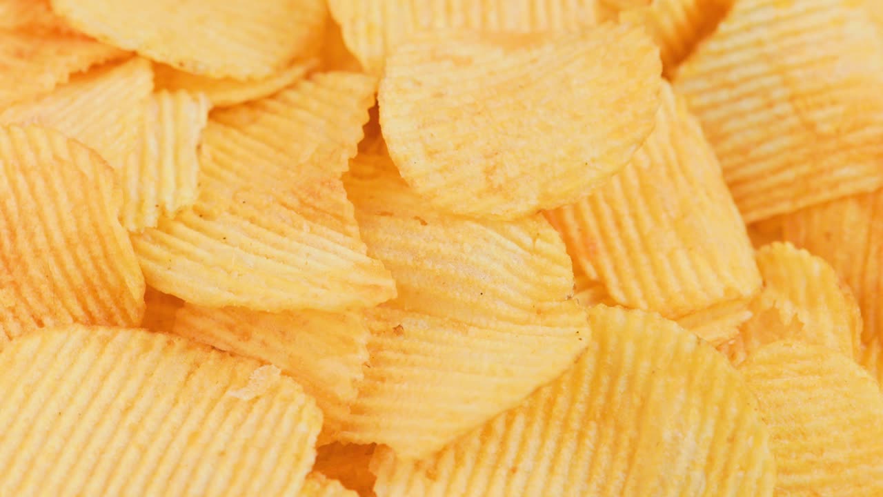 schegge di patate gialle ondulate rotanti a fotogramma completo sullo sfondo in primo piano
