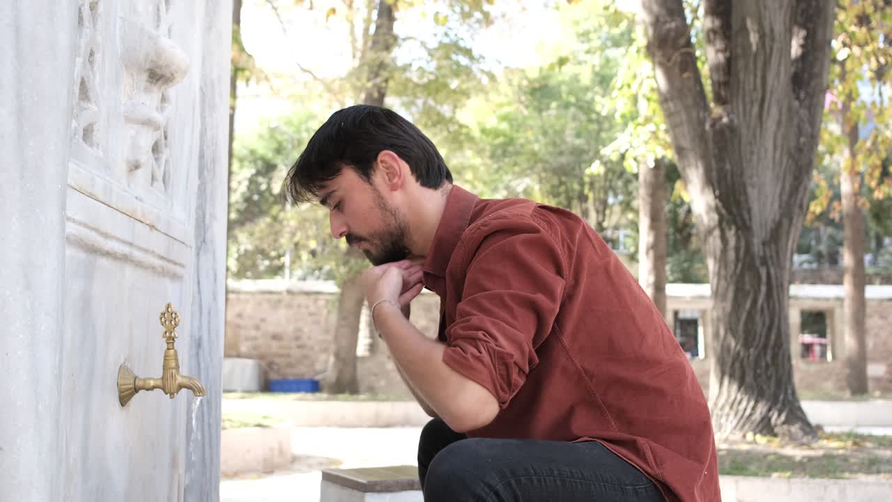 young muslim bearded man washing his head while performing ablution at the fountain of the mosque, bearded man performing religious ritual