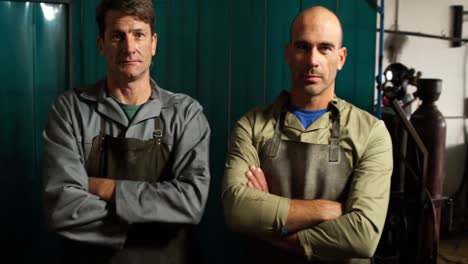 welders standing with arm crossed in workshop