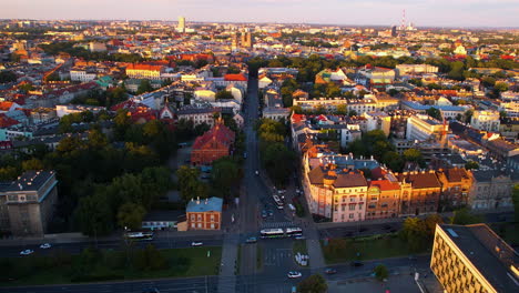 Vuelo-Aéreo-Sobre-La-Ciudad-Dorada-De-Cracovia-Por-La-Noche-Con-Iluminación-De-Edificios-Al-Atardecer-Y-Conducción-De-Automóviles-En-La-Carretera,-Polonia