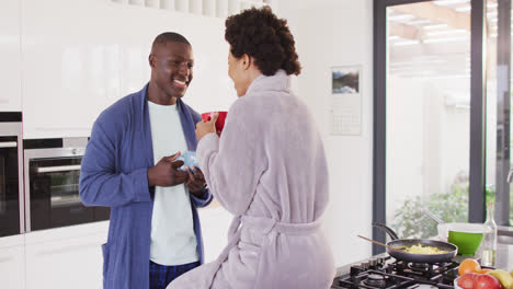 Video-of-happy-african-american-couple-drinking-coffee-together-in-kitchen