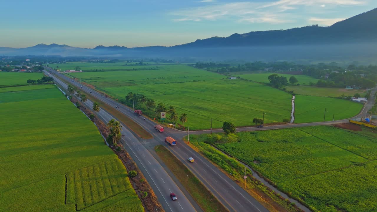 Duarte Highway in rural Dominican Republic, surrounded by mountains and green farmland. Aerial orbit view