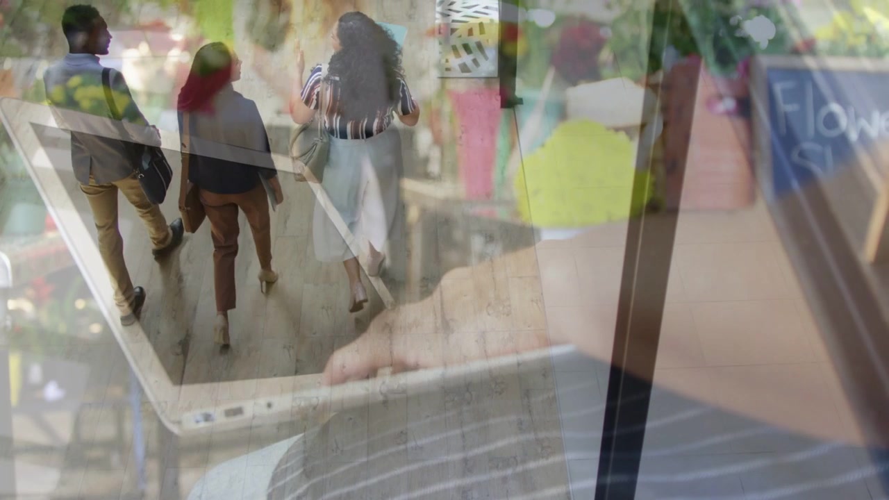 Woman holding tablet and tapping screen, reviewing retail shopper flow as three walkers walking