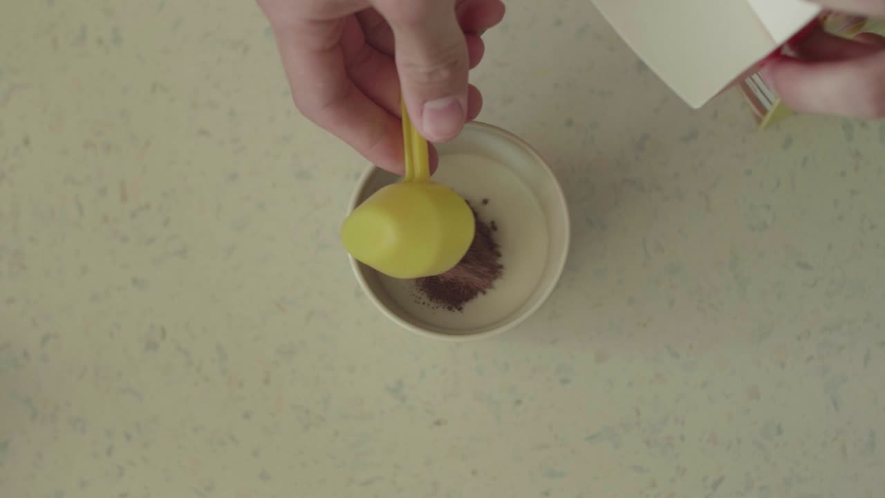 [TOP SHOT] of someone putting cacao in a mug with milk