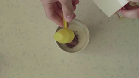 [top shot] of someone putting cacao in a mug with milk