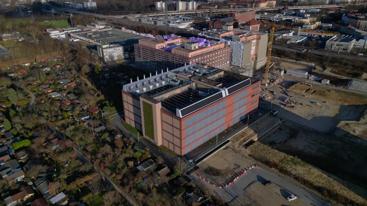 Edificio moderno di un grande data center, con unità di raffreddamento, pannelli solari e un tetto verde per operazioni sostenibili. Maestosa ripresa aerea con drone, camera puntata, volo inverso del drone