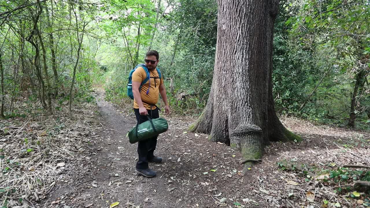 Lonely camper walking and looking around for camping spot in forest