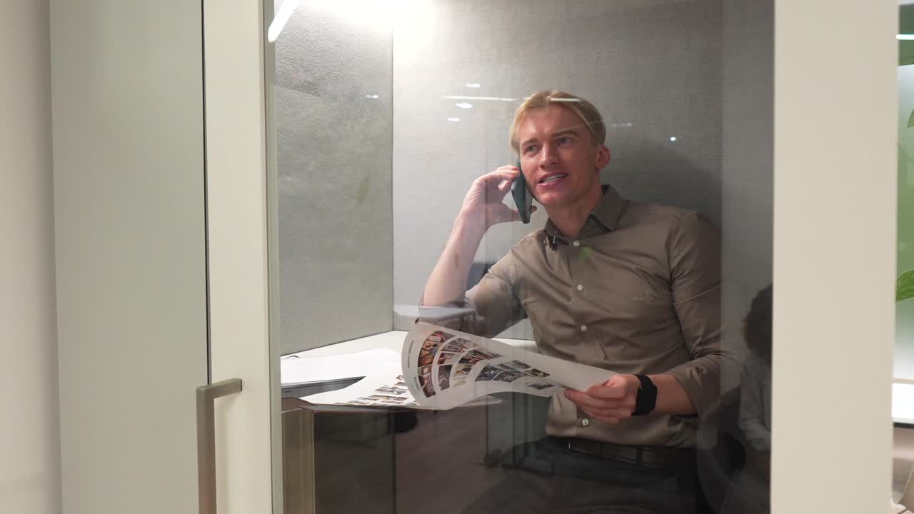 Mann som snakker i telefon i kontorbås