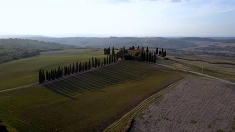 Villa-with-cypress-tree-lined-dirt-road-in-Tuscany-Italy,-Aerial-dolly-in-shot