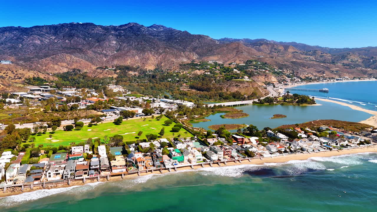 Beautiful waves roll to the houses located on the sandy beach. Stunning panorama of Malibu, Los Angeles County, California, USA from drone
