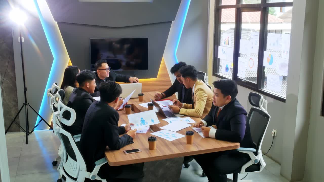 Dynamic business team collaborates on strategy analyzing charts in modern boardroom