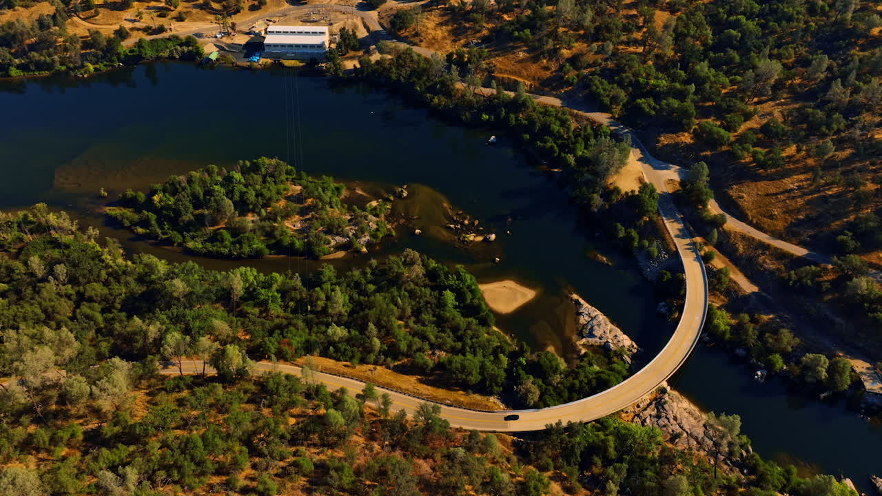 Beautiful blue lake with bridge over it and car moving by highway. Scenery of Sierra National Forest, California, USA from top.