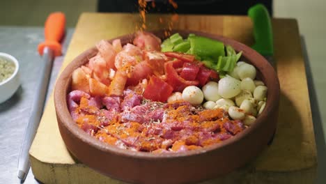 the chef hand puts spices on the raw food in the casserole prepared for the oven