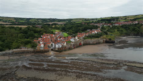 establishing aerial drone shot of robin hood's bay at low tide on overcast day