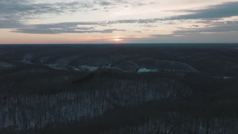 peaceful forest at sunset in middle tennessee, light snow covering hills and trees, slow aerial push in.