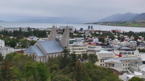 aerial view of akureyri church, town buildings, harbor and fjord, cinematic drone shot