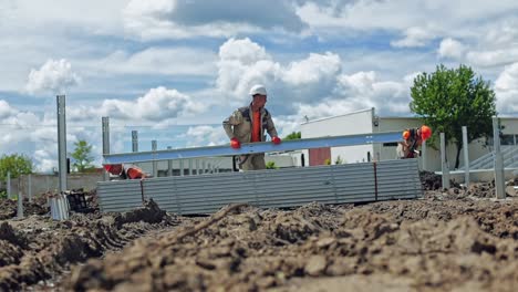 construction solar farm. workers in protective uniform build metal basis on the ground in summer day. slow motion.