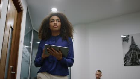 african american executive walking office looking corporate tablet in company.