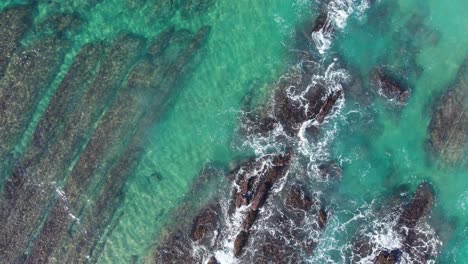 Waves-crashing-and-water-washing-on-ridges-of-soar-cliff-coastline-in-Playa-de-Tagle,-Spain,-Spanish-shore