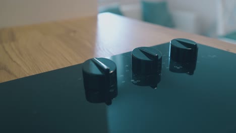 knobs at black electric stove at wooden counter in kitchen