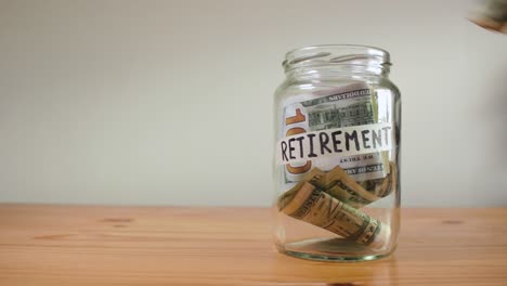 a glass jar filled with money labeled for retirement savings