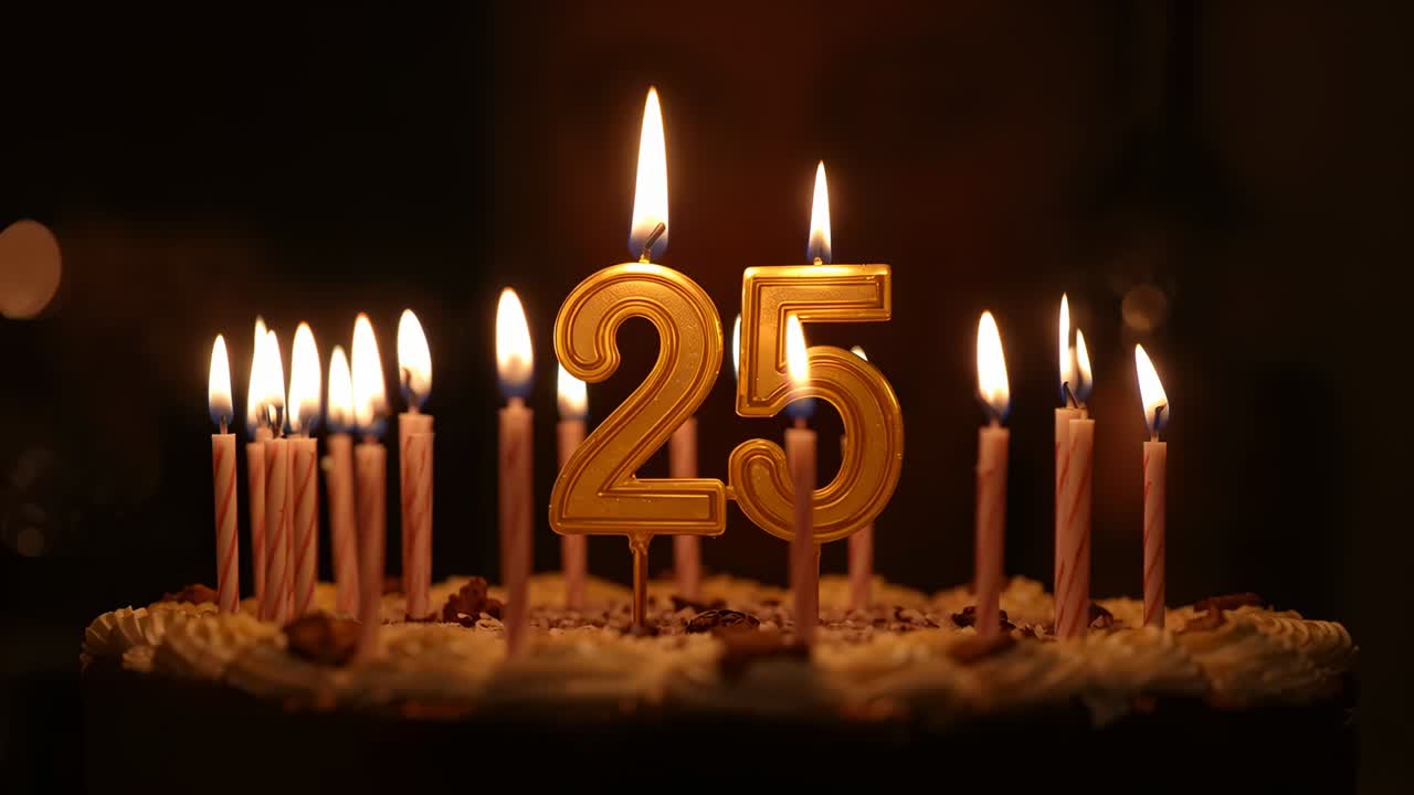 Lit candle flames flickering on frosted cake in dim room, celebrating 25th with golden 25 candle