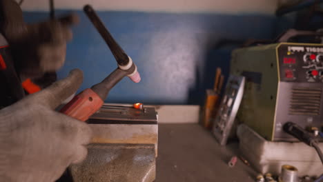 welder in protective gear welding metal with a tig welder in an industrial setting